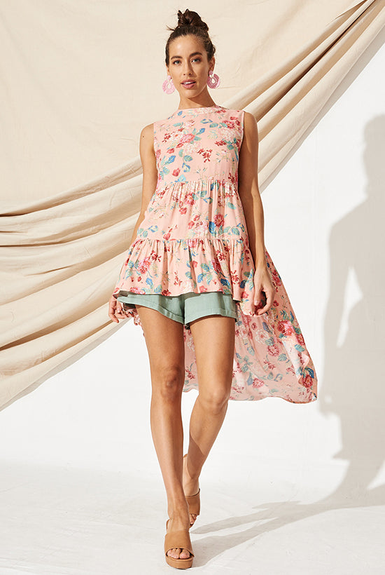 Women in a long flowy pink floral top, over the top of sage cotton shorts