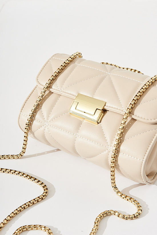Cream padded clutch back with gold closure and chain.