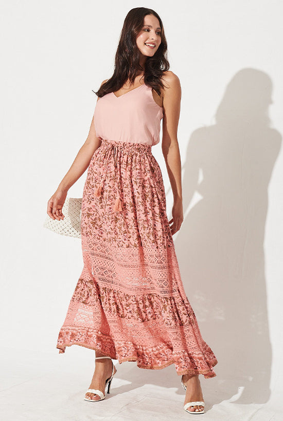 Women in a light rose camisole top tucked into a paneled pink maxi skirt.