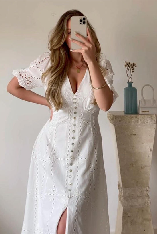 Image of a women taking a photo in a mirror in a white midi dress